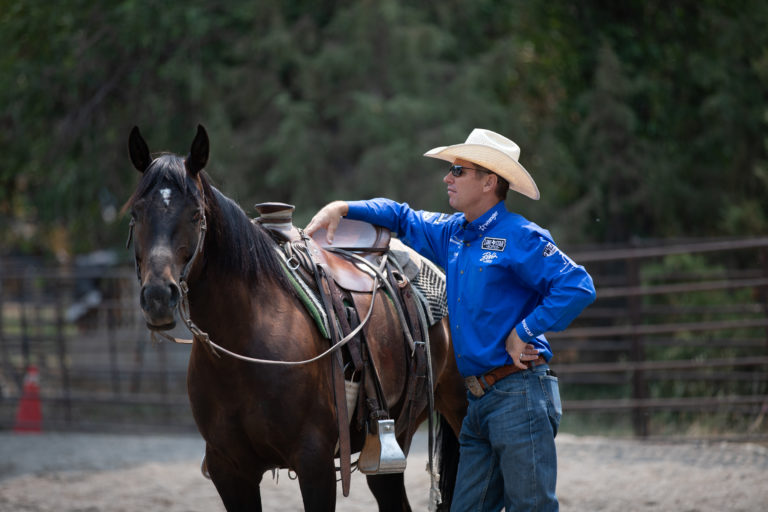 Brad Barkemeyer stands with his bay cutting and ranch horse at a clinic.