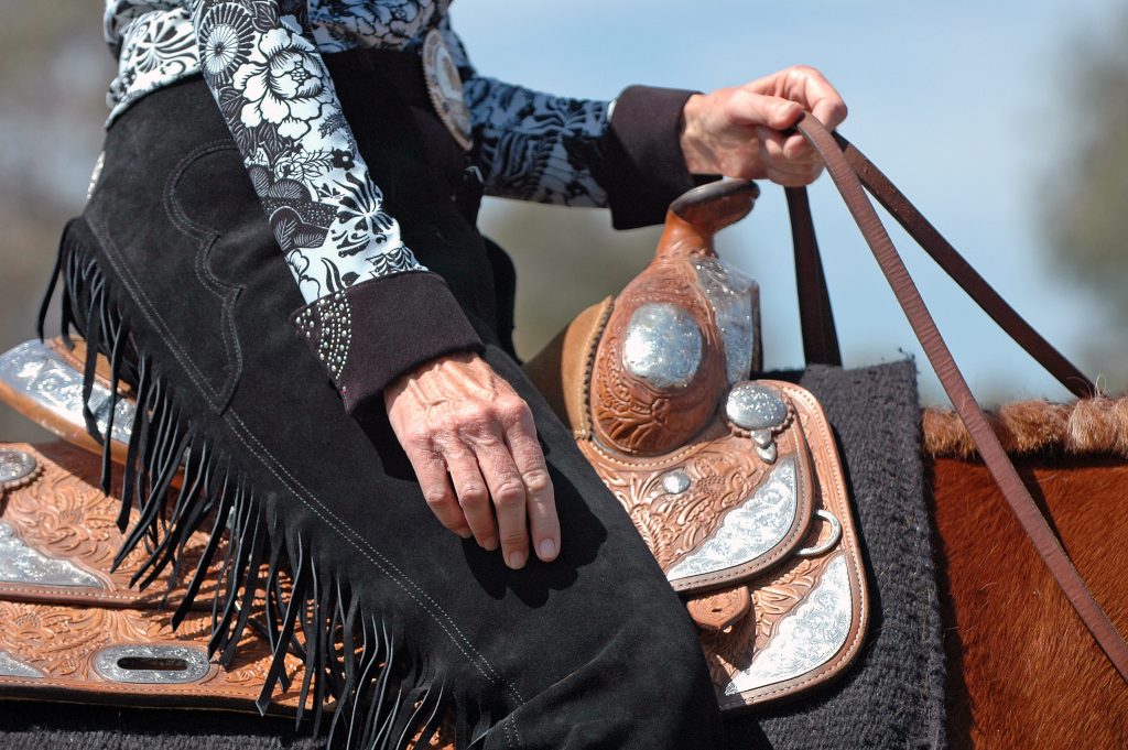 Woman riding show horse before horse show, western saddle and western horse.