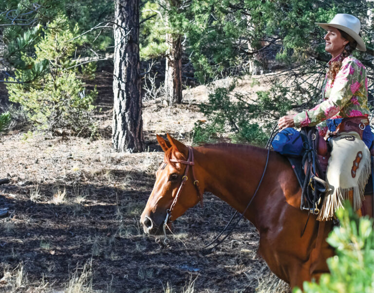 Julie Goodnight trail riding with her horse.