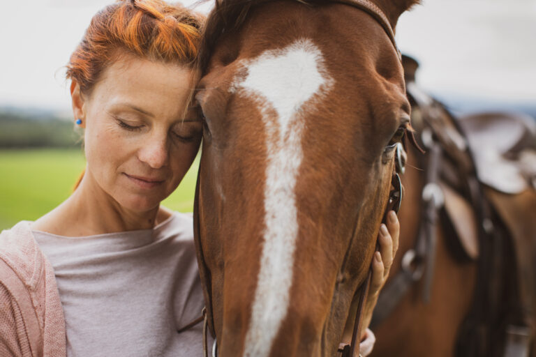 Pretty, young, redhead woman with her lovely horse, during her favorite leisure