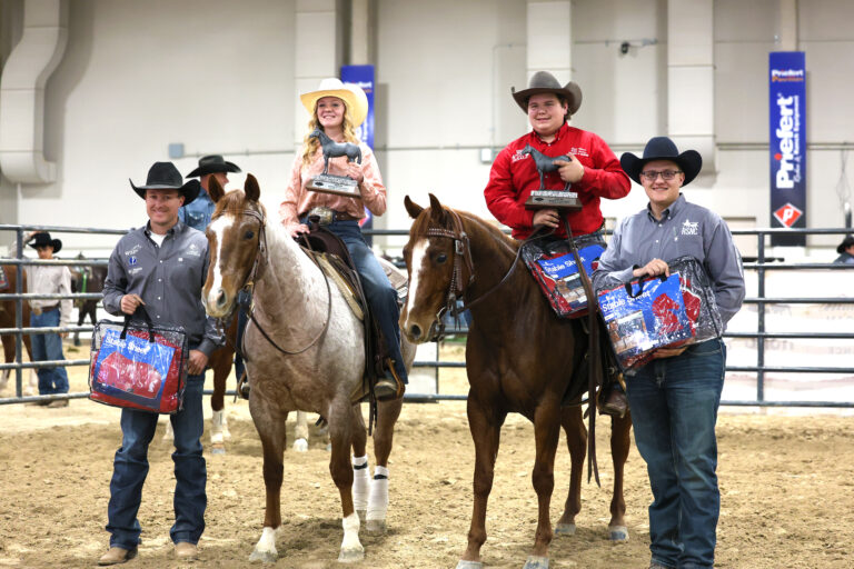 Two men give awards to two horseback riders