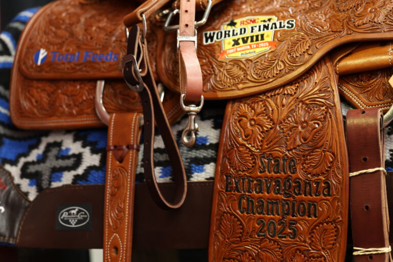 Close-up of a tooled leather saddle awarded at the 2025 Cinch RSNC World Finals in Fort Worth, Texas, featuring 'State Extravaganza Champion 2025' and sponsor logos.