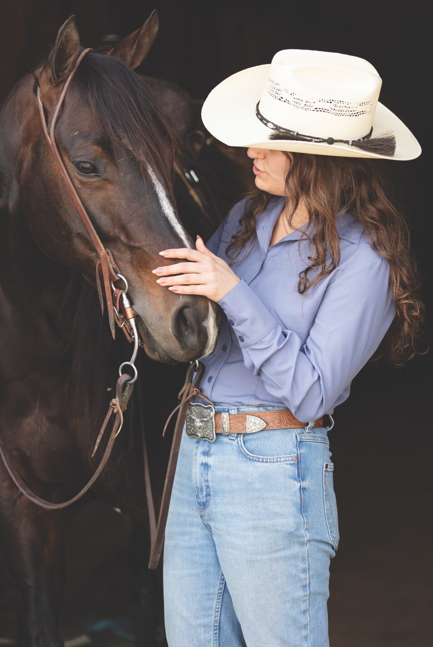 Rider in a dusty-blue CR RanchWear show shirt, straw hat, and Wrangler jeans standing with a horse