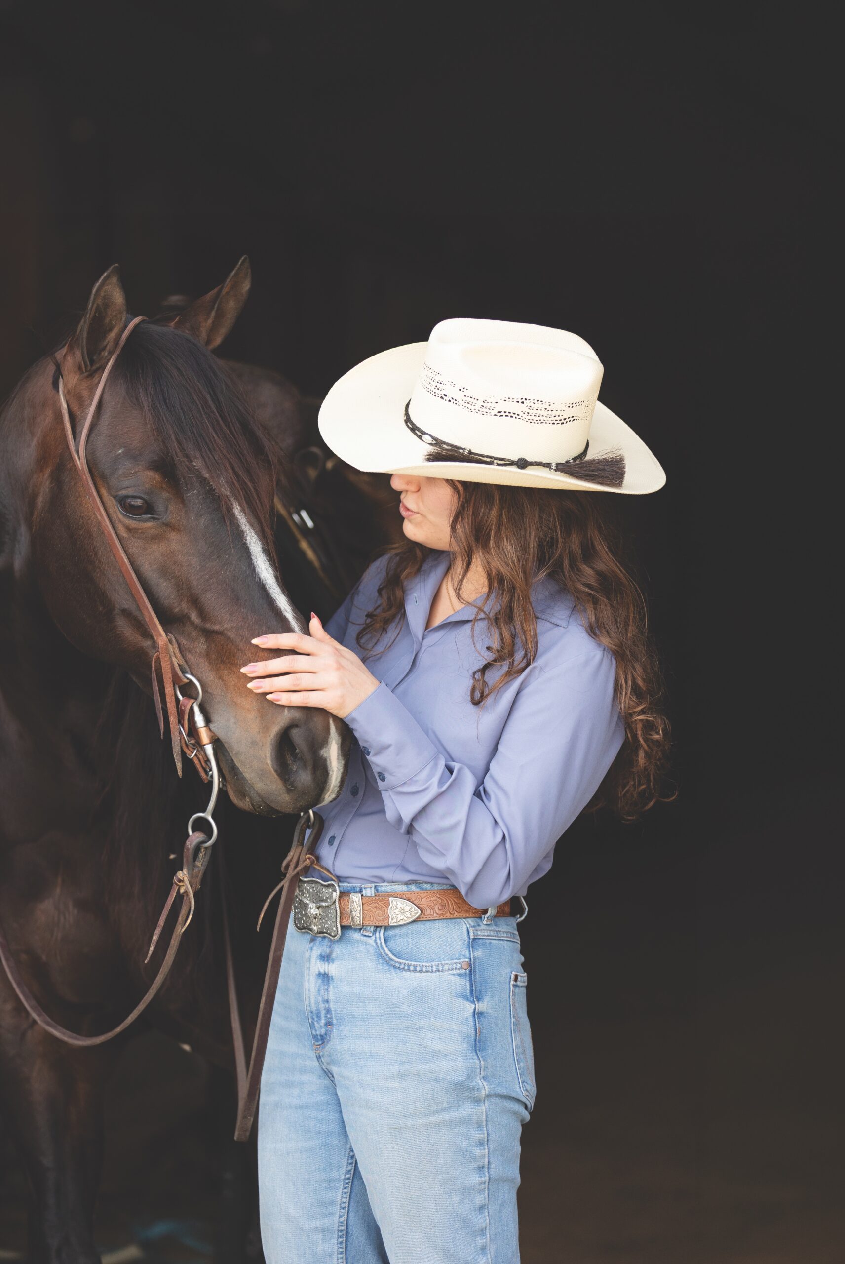 Rider in a dusty-blue CR RanchWear show shirt, straw hat, and Wrangler jeans standing with a horse
