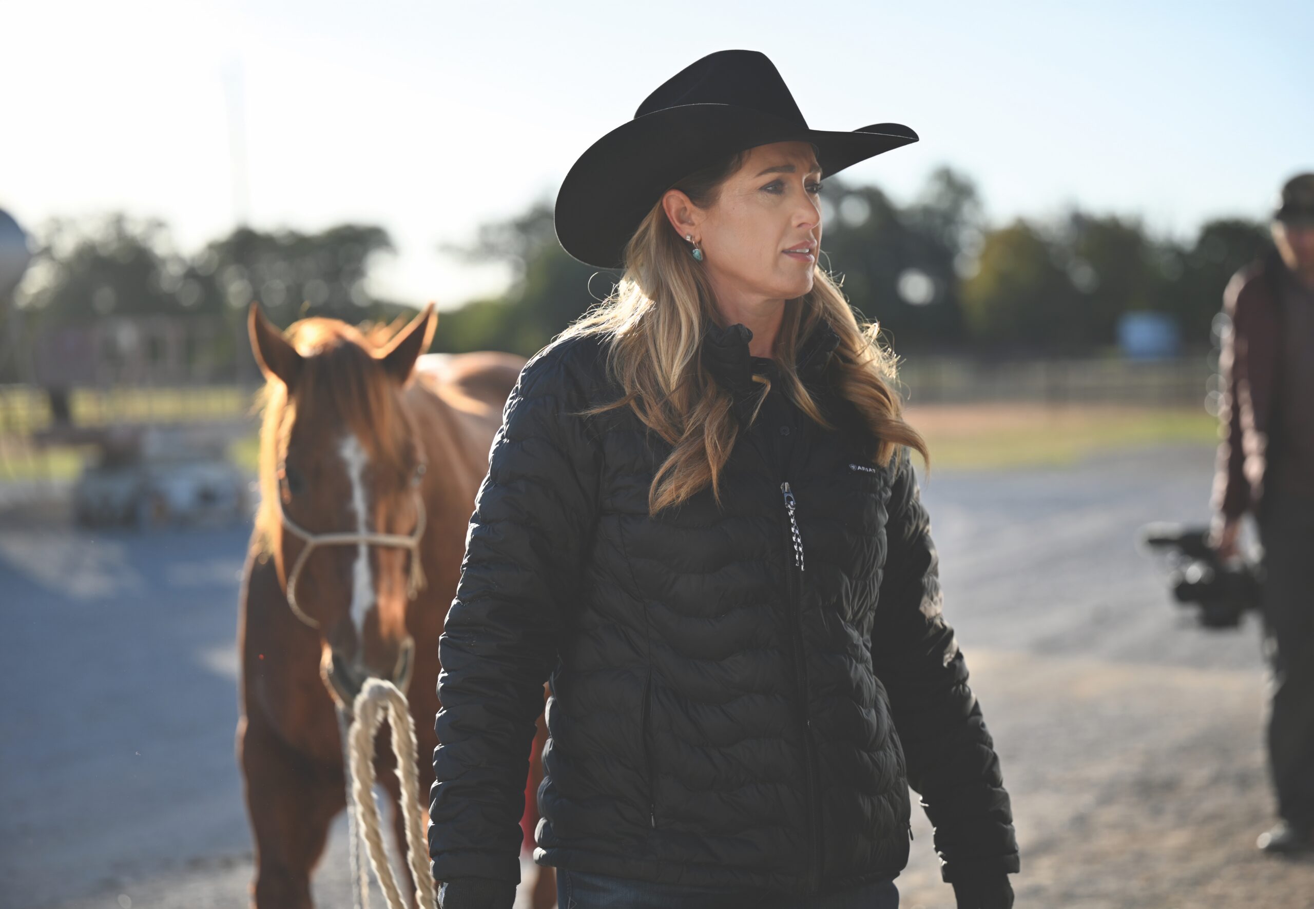WPRA world champion roper Jackie Crawford stands beside a saddled sorrel horse at a ranch