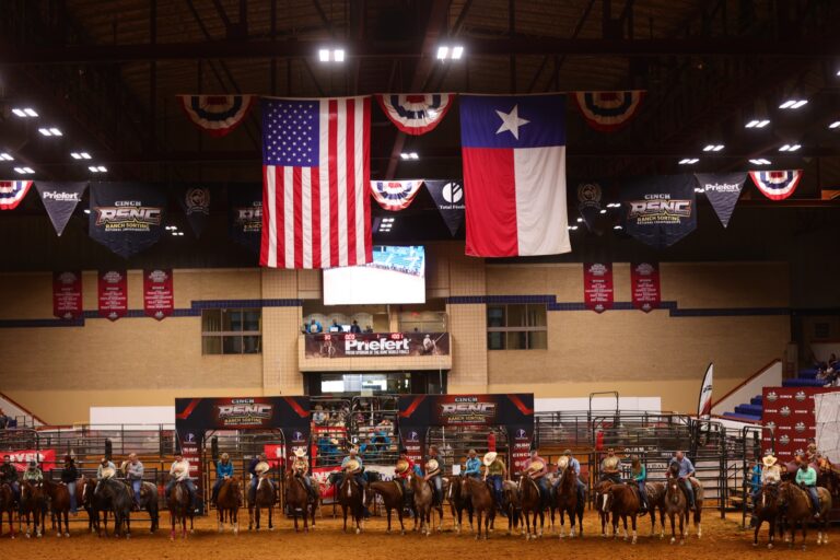 Competitors line up on horseback beneath the U.S. and Texas flags at the 2026 Cinch RSNC World Finals in Fort Worth