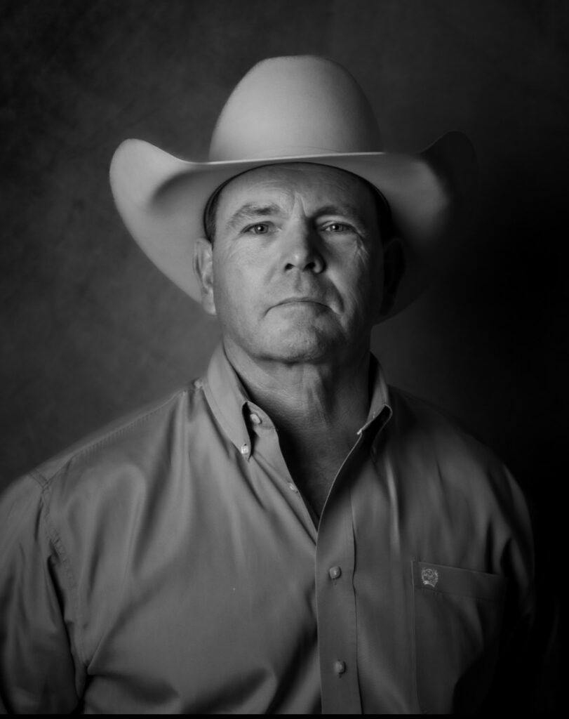 Black-and-white portrait of Bill Norman in a cowboy hat and button-down shirt.