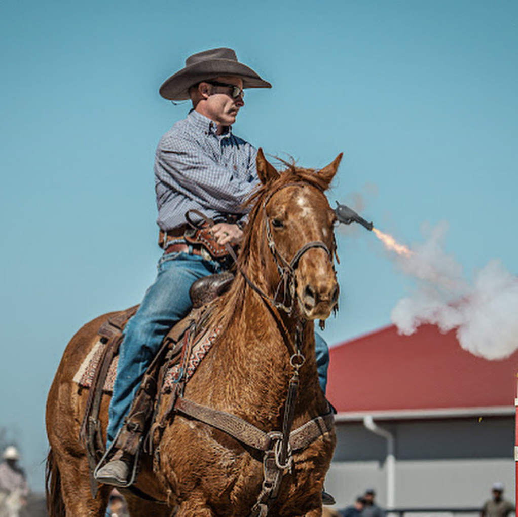 Jeremy Svejcar fires a revolver from the back of a sorrel horse during a cowboy mounted shooting run.